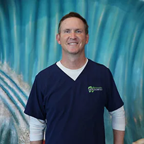 Dr. Joseph Whitesides, orthodontist, in navy scrubs against a blue backdrop