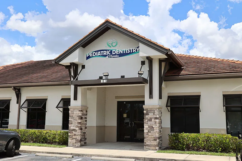 The exterior of the Naples office of Pediatric Dentistry of Florida, a single-story building with a stone entry and the practice sign