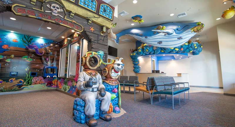 The Naples lobby: the S.S. Flossy pirate nook, a deep-sea diver statue with Shades the dog, and a blue whale sculpture over the waiting chairs