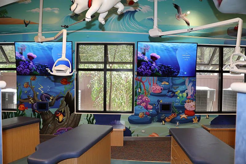 Naples treatment area with floor-to-ceiling undersea murals and screens above the windows showing underwater video